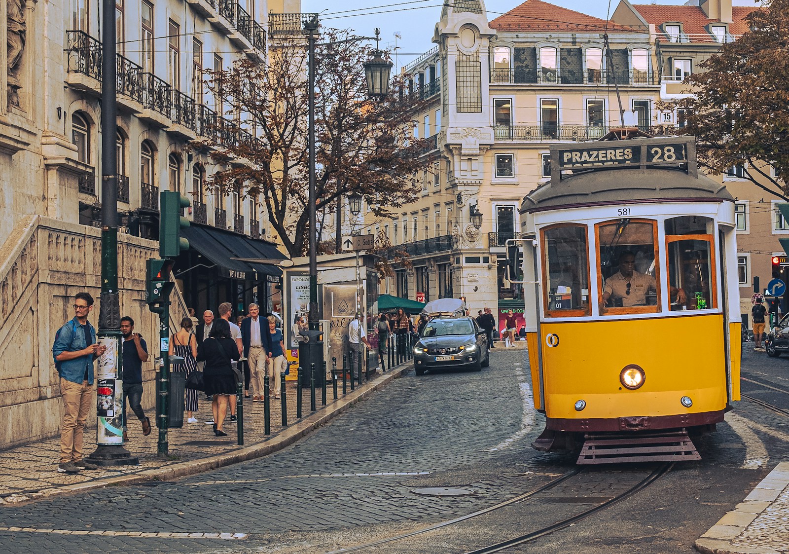 Calle de Lisboa: tranvía amarillo, gente andando, fachadas de azulejo