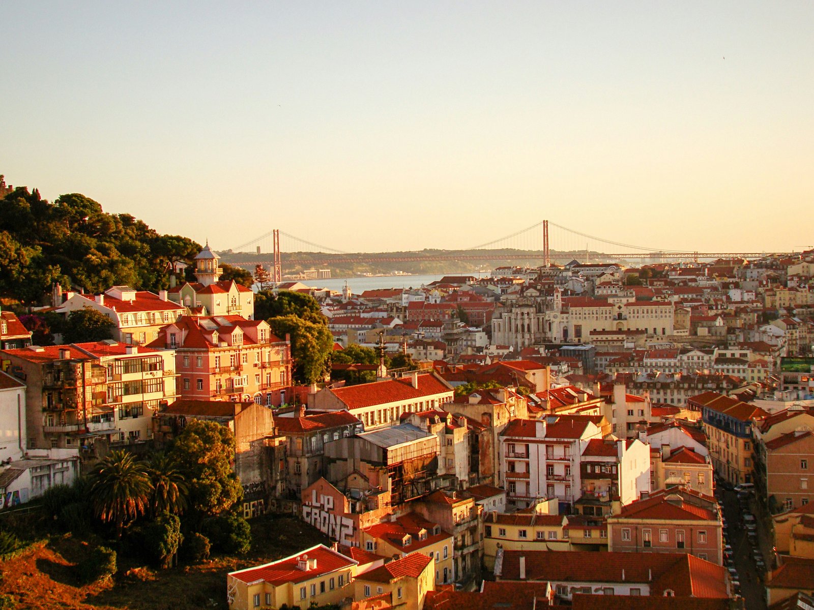 Lisboa ao pôr do sol: os telhados da Baixa, a Ponte 25 de Abril e o Tejo ao fundo